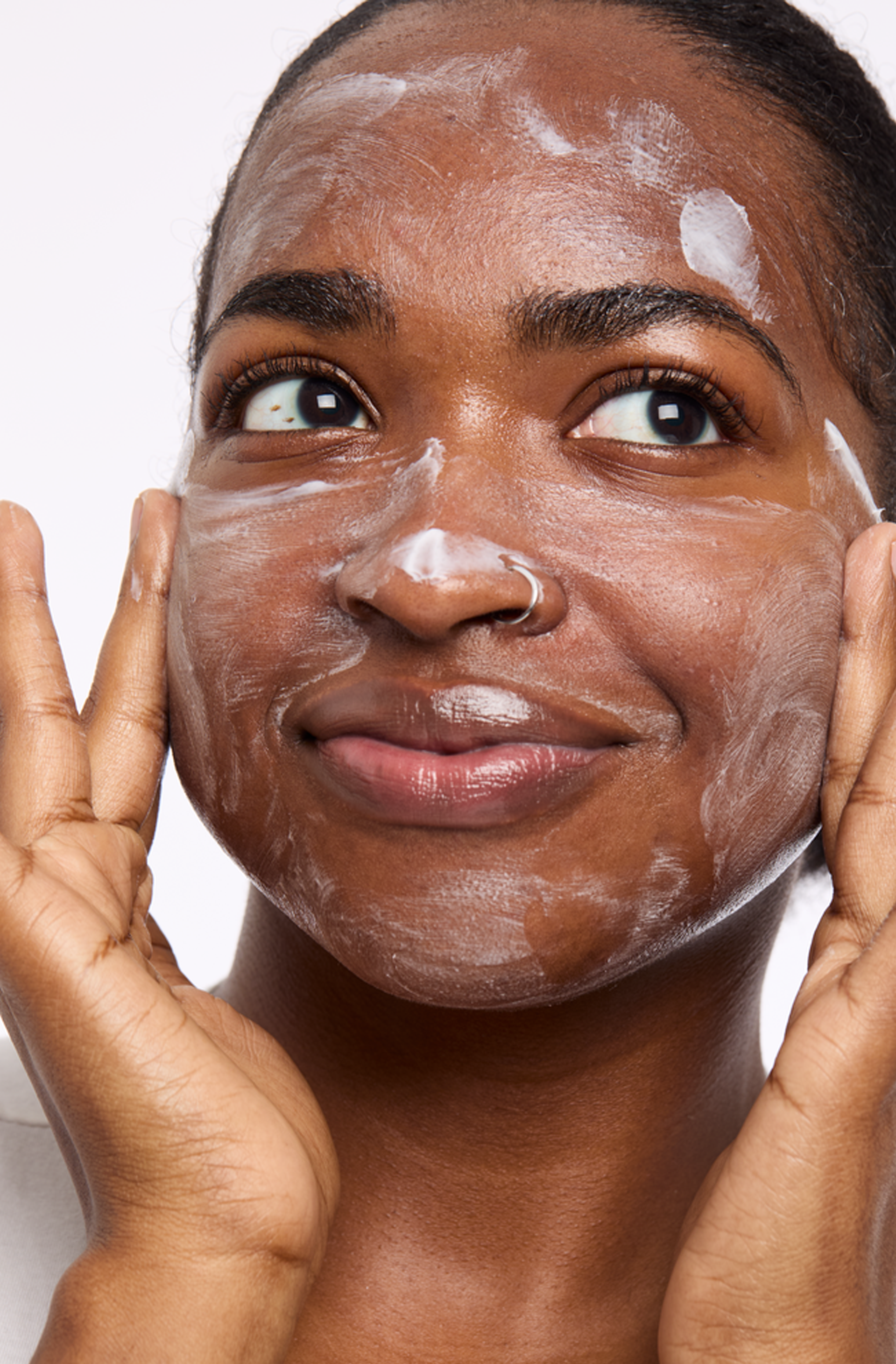 A person holds their hands up near their face, palms facing outward using a Mary Kay cleanser to wash their face.